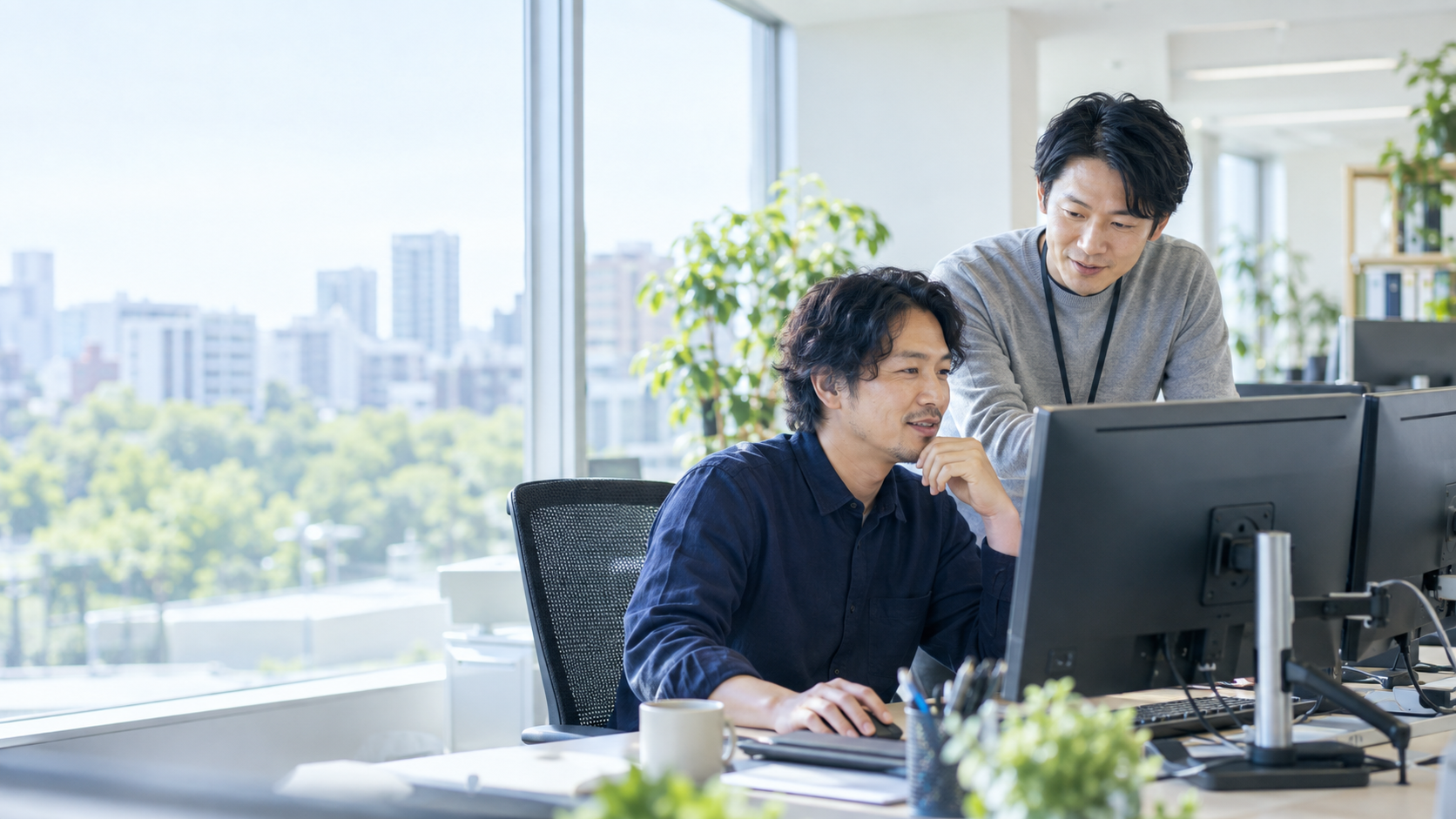 明るいオフィスでシステム運用について確認する二人のIT技術者